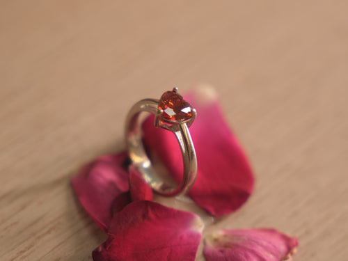 Close view of the deep red heart American Diamond in its prong setting.