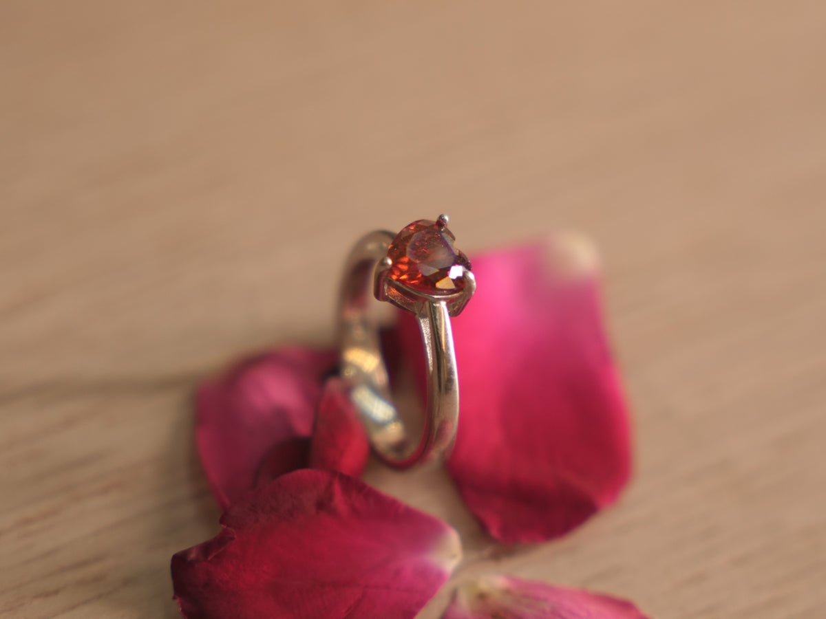The red heart ring standing upright on a pale wooden surface.