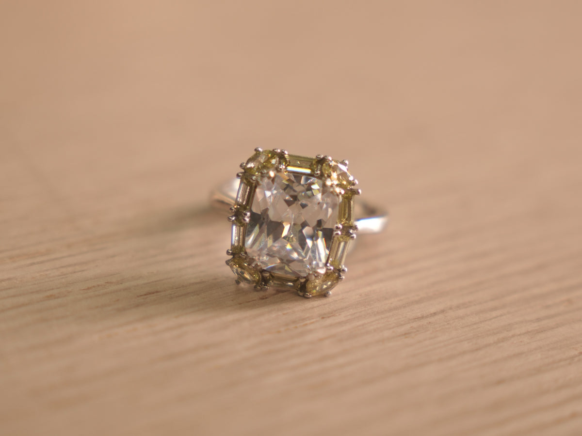 Sterling silver cocktail ring with a large colourless crystal centre framed by pale yellow and green stones.