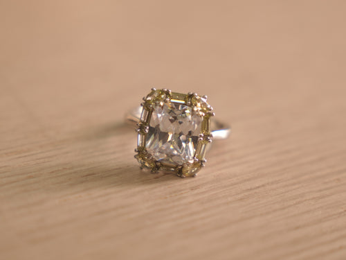 Sterling silver cocktail ring with a large colourless crystal centre framed by pale yellow and green stones.