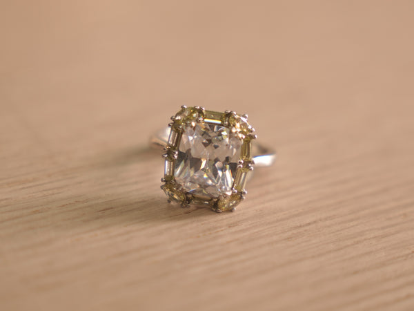 Sterling silver cocktail ring with a large colourless crystal centre framed by pale yellow and green stones.