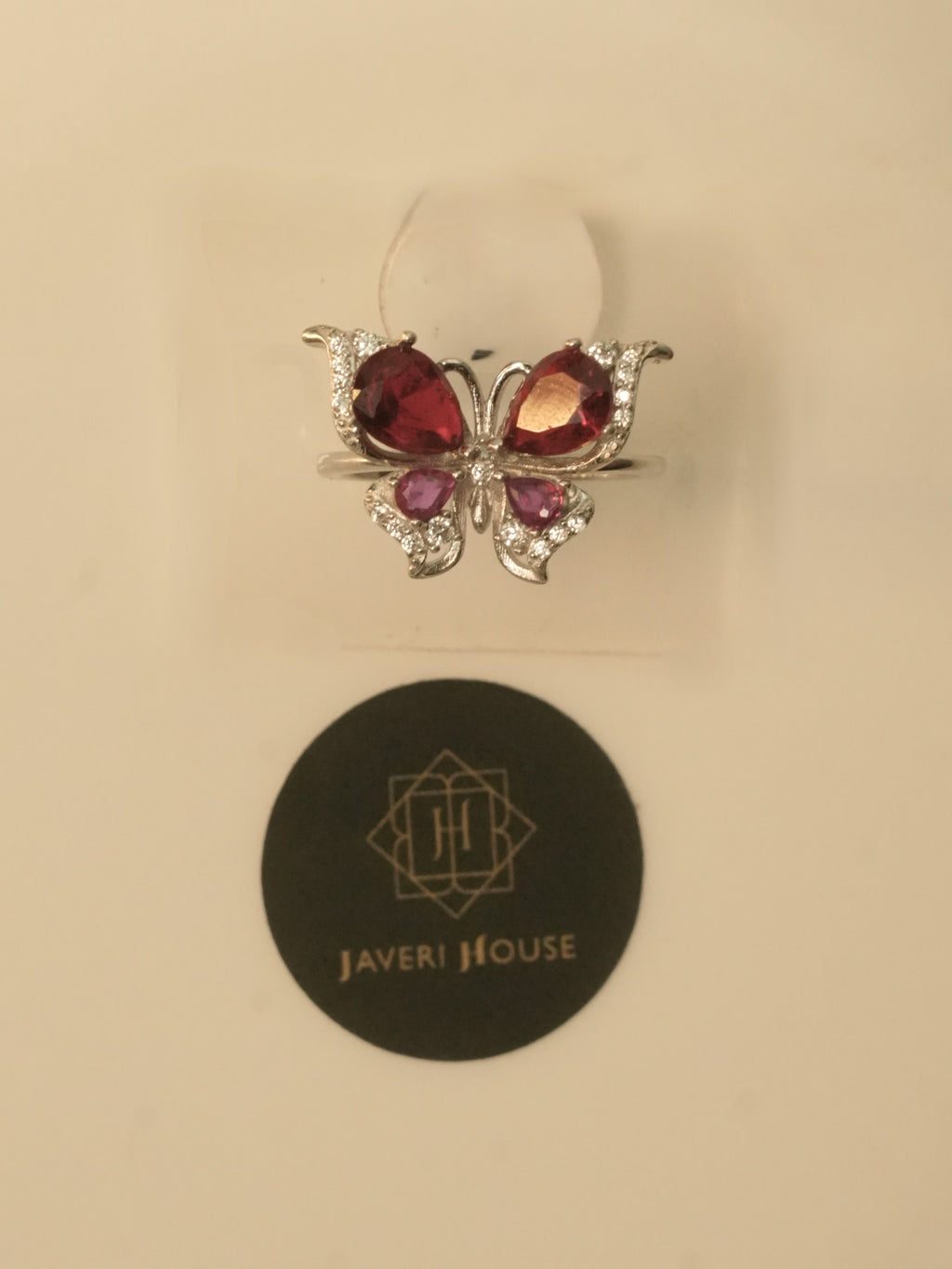 The butterfly ring seen from the front, with light passing through the red stones.