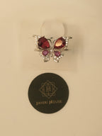 The butterfly ring seen from the front, with light passing through the red stones.