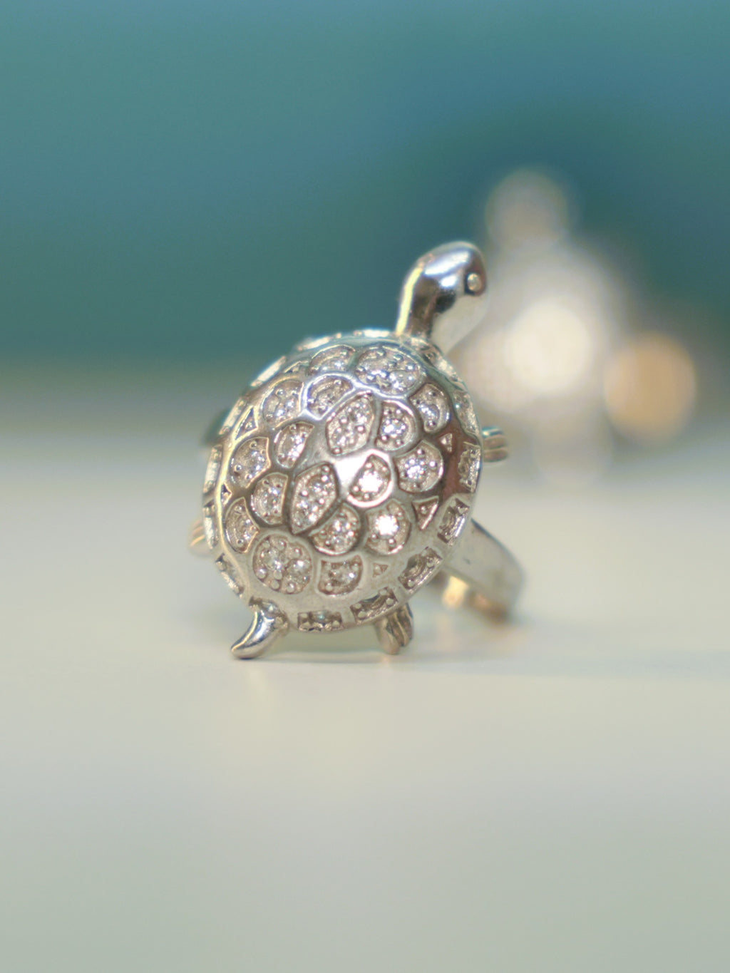Sterling silver tortoise ring with an American Diamond pave shell, standing on a pale surface.