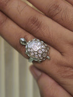 The tortoise ring worn on a hand, showing its scale on the finger.