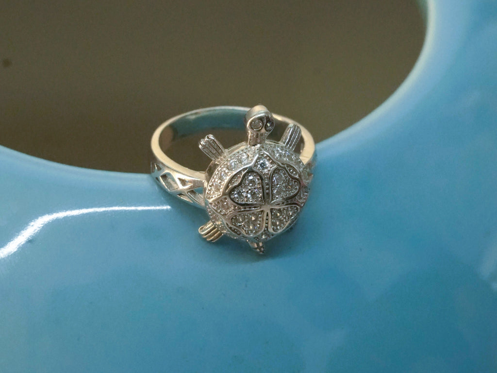 The tortoise ring resting on the rim of a blue vase, showing the lattice cut shoulder.