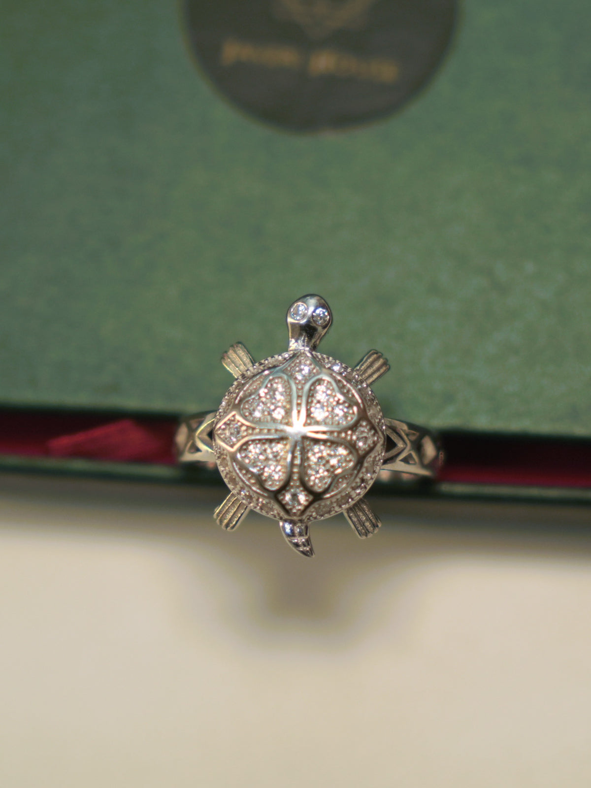 Top view of the tortoise ring, showing the four pave set petals and the stone set eyes.