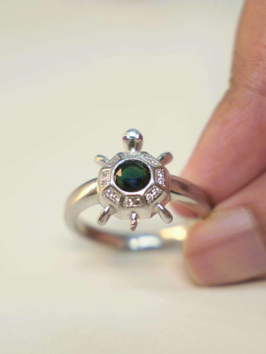 Sterling silver tortoise ring with an eight sided shell and a deep blue centre stone, held in the hand.