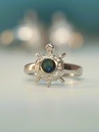 Front view of the octagon tortoise ring standing on a pale surface.