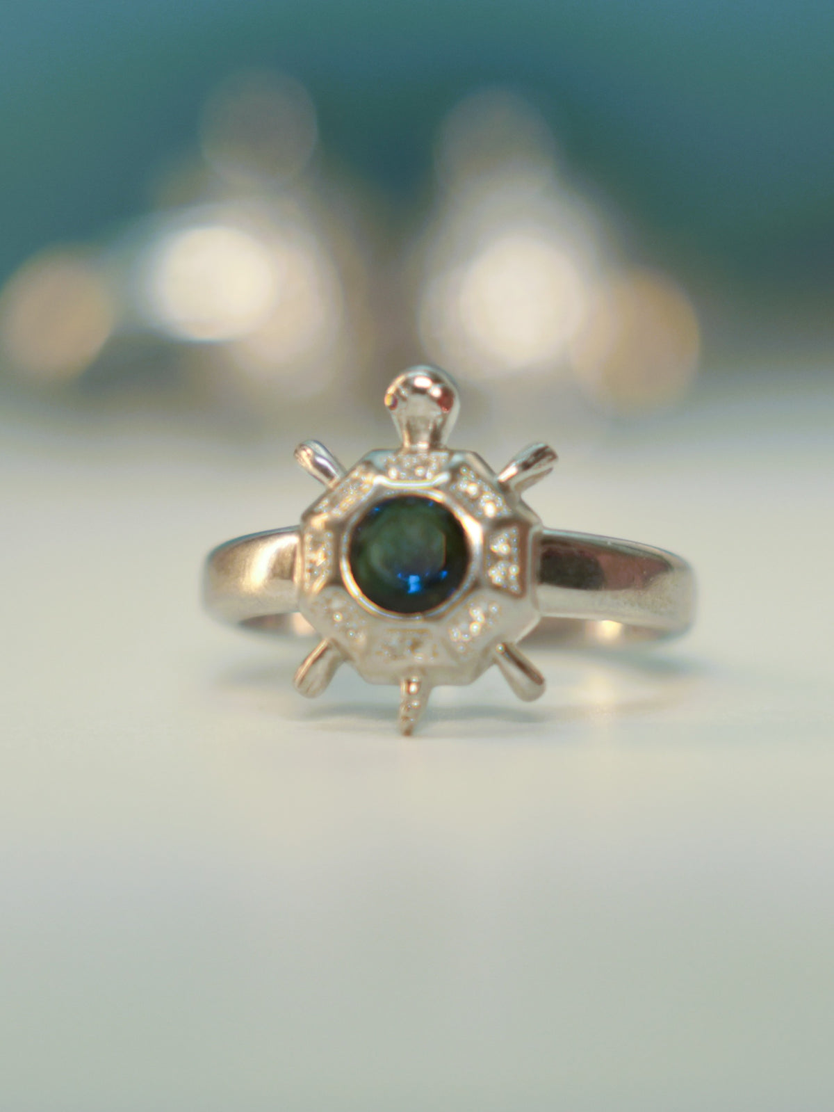 Front view of the octagon tortoise ring standing on a pale surface.