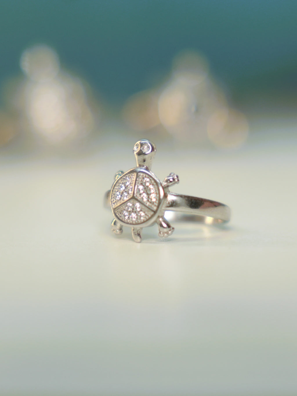 Front view of the small tortoise ring standing on a pale surface.