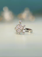 Front view of the small tortoise ring standing on a pale surface.