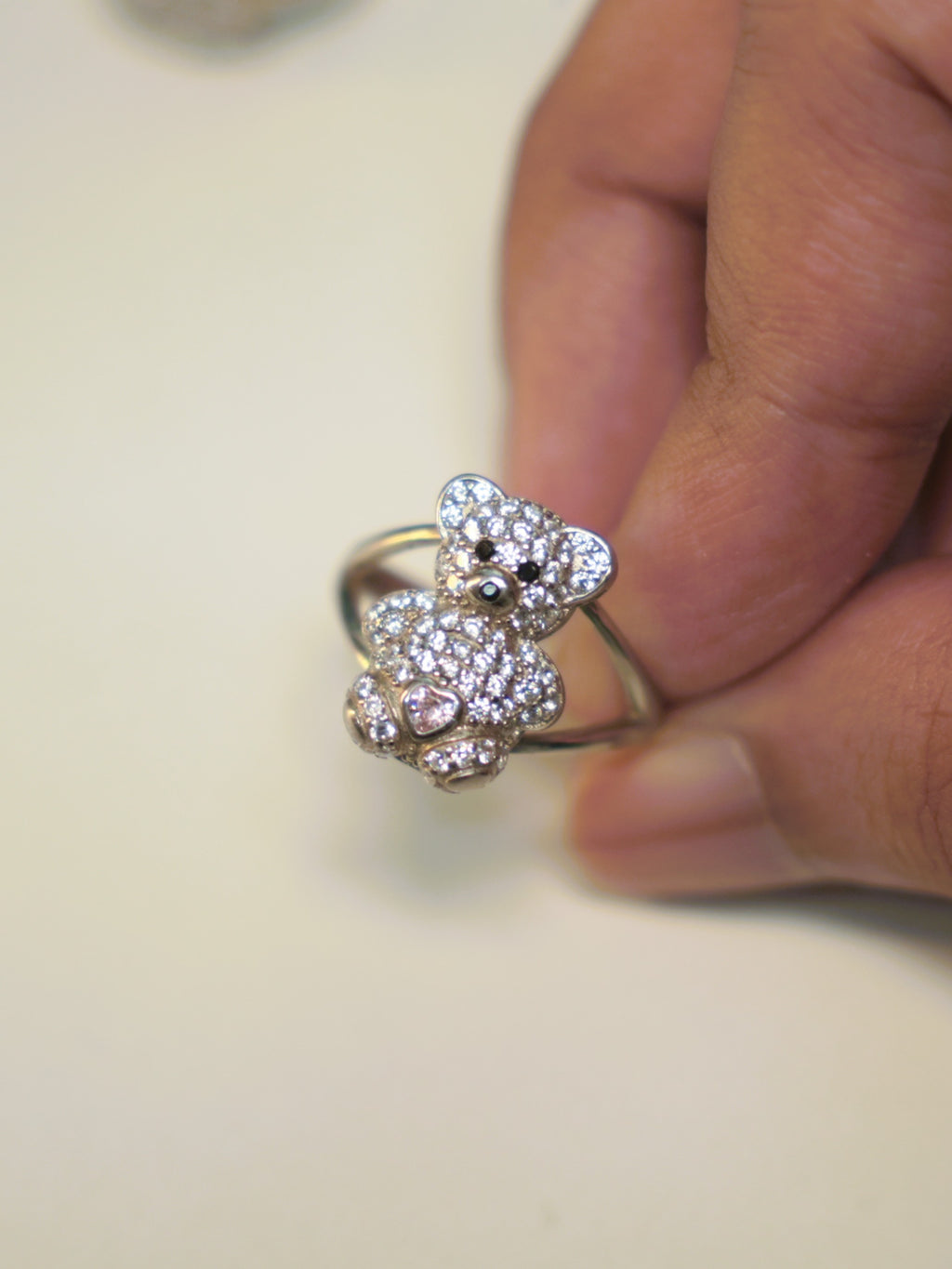 The teddy bear ring held between two fingers, showing the split band.