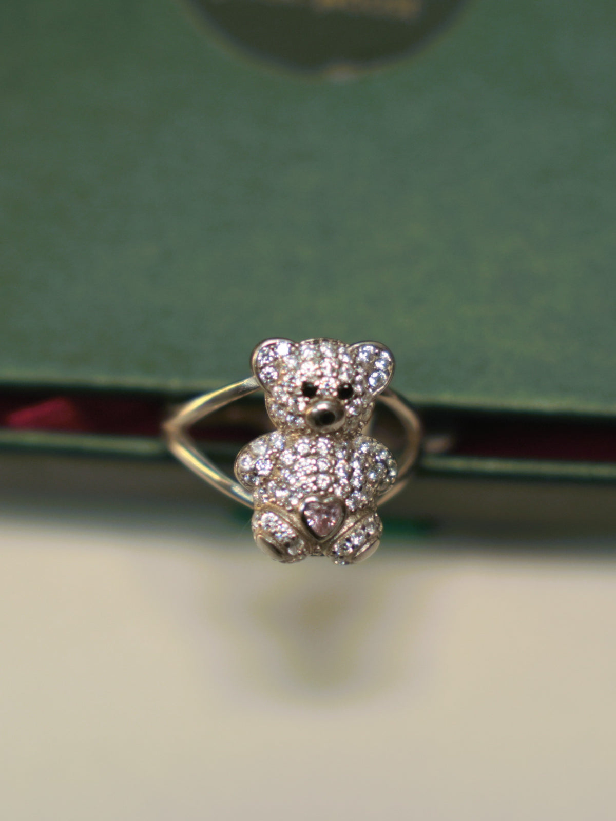 Front view of the teddy bear ring, showing the black eyes and the pink heart stone.