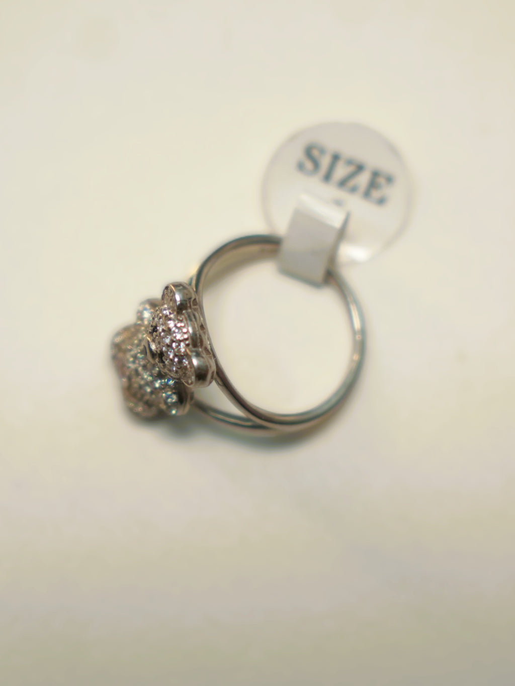 The teddy bear ring seen from the side with its size tag attached.