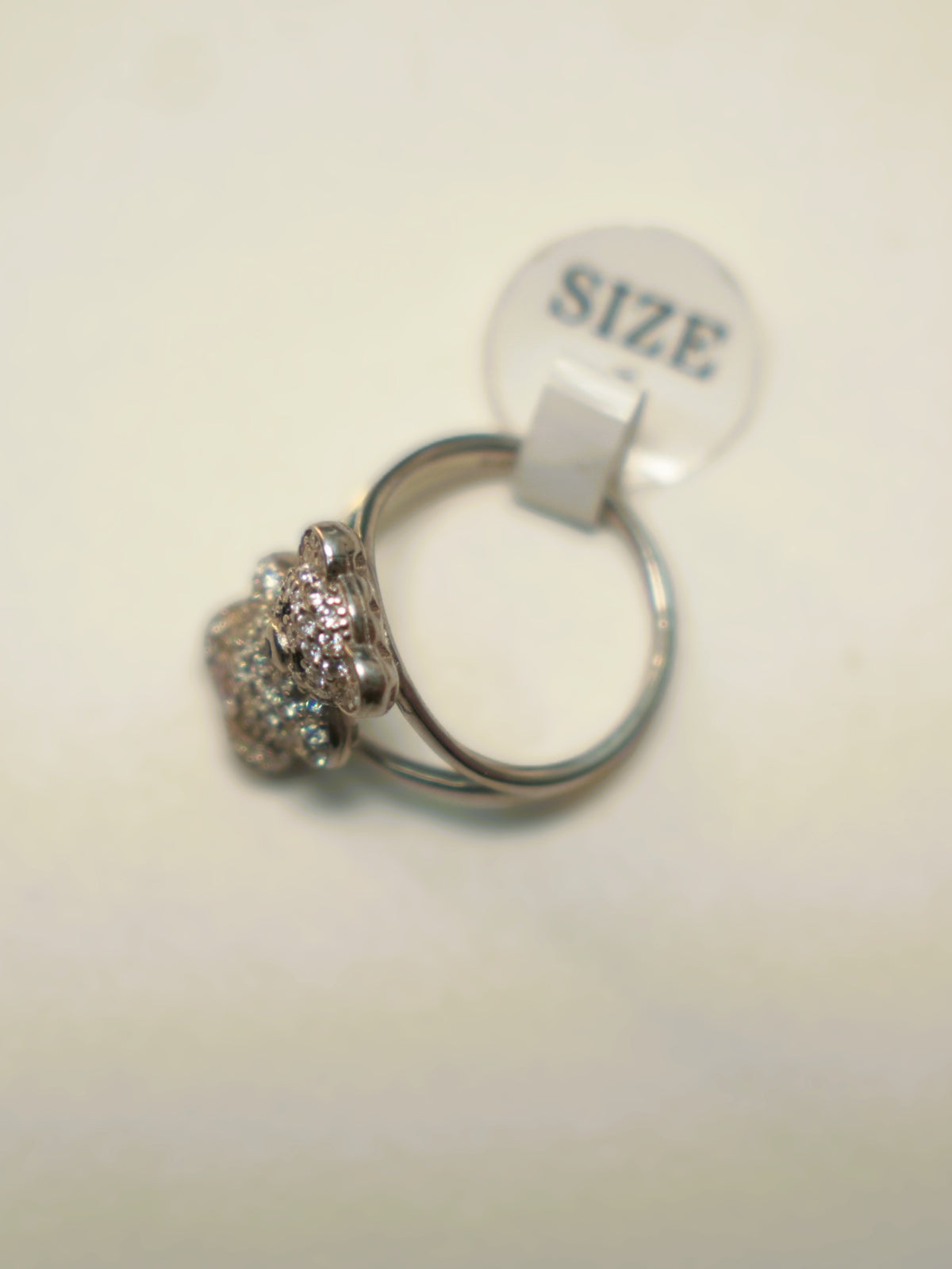 The teddy bear ring seen from the side with its size tag attached.