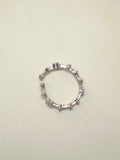 Slim open sterling silver band set with baguette American Diamonds, lying on a pale surface.