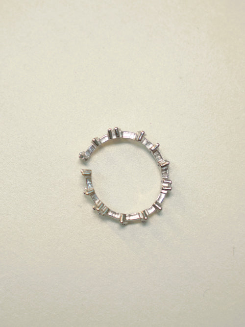 Slim open sterling silver band set with baguette American Diamonds, lying on a pale surface.
