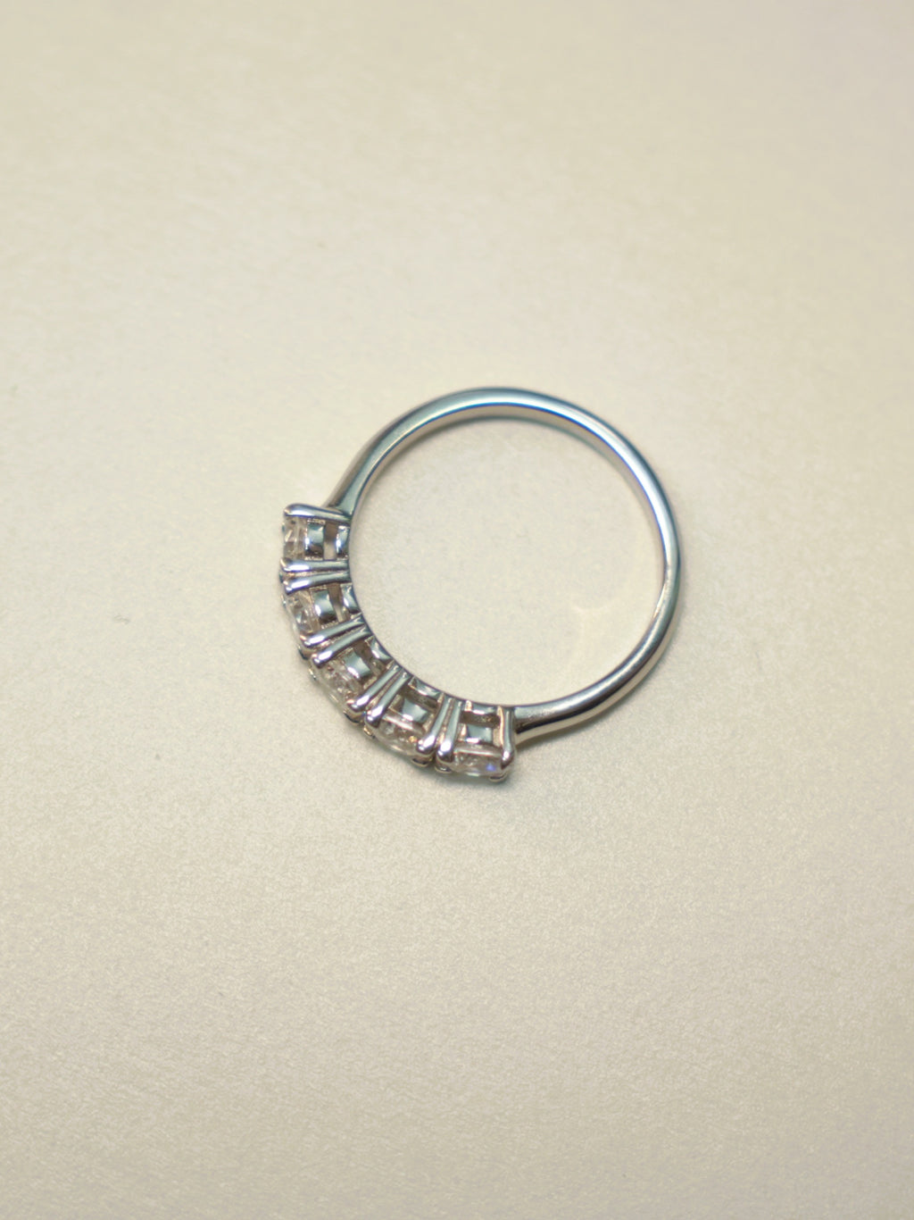 Side view of the five stone ring, showing the shared prongs and the plain band.