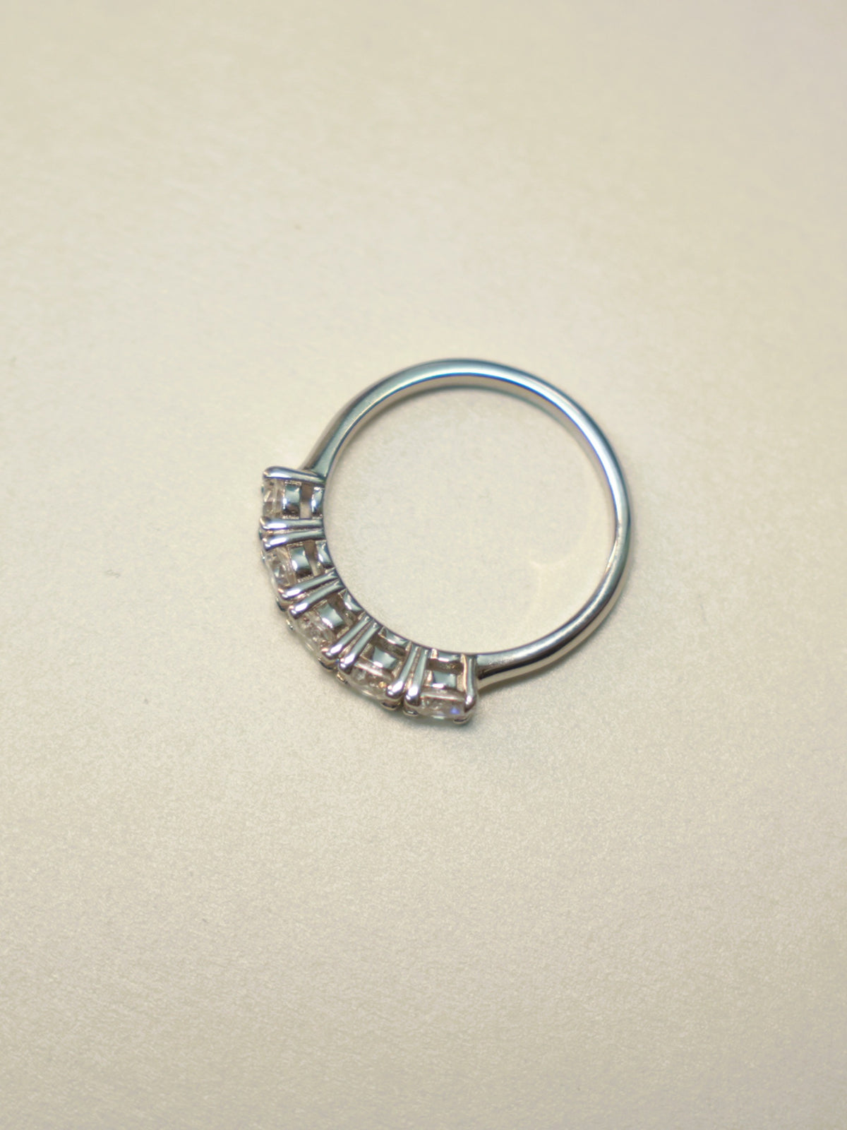 Side view of the five stone ring, showing the shared prongs and the plain band.