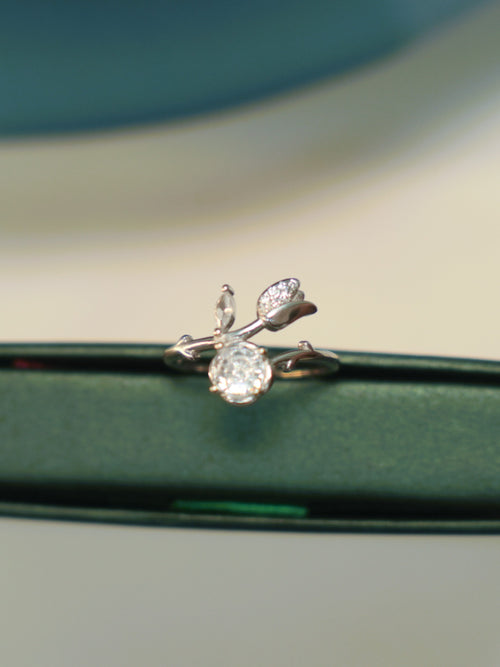 Sterling silver bypass ring with a round American Diamond and a pave set tulip bud, standing on the edge of a green box.