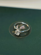 The tulip bud ring lying on a dark green surface, showing how the two ends pass each other.