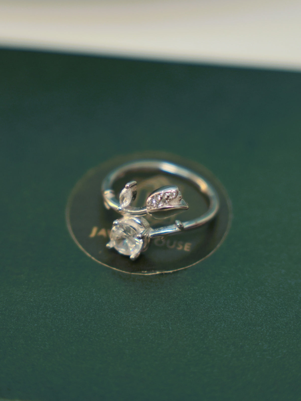 The tulip bud ring lying on a dark green surface, showing how the two ends pass each other.