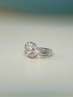 Side view of the wave ring standing on a pale surface, showing the channel set baguettes.