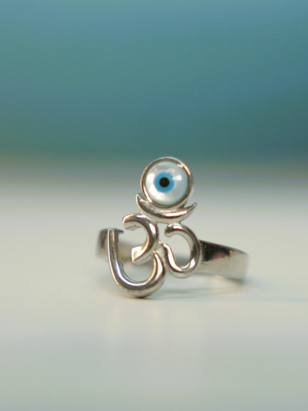 Sterling silver Om ring with a round blue and white evil eye disc above the symbol.