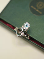 The Om and evil eye ring on the edge of a green box, showing the plain band.