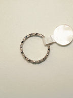 The heart band ring lying flat with its size tag attached, showing the hearts running around the band.