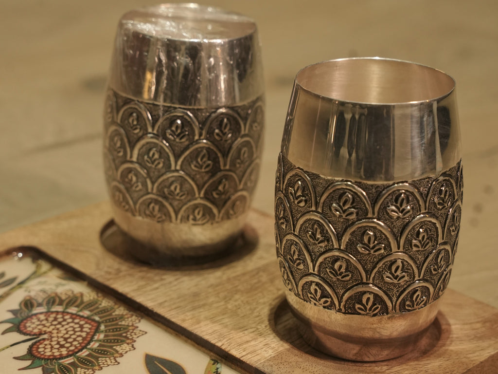 The two engraved silver drinking glasses side by side on a serving tray.