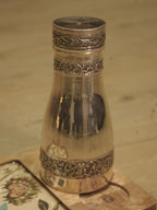 The silver carafe beside its lid cup, showing the tapering bright body and chased bands.