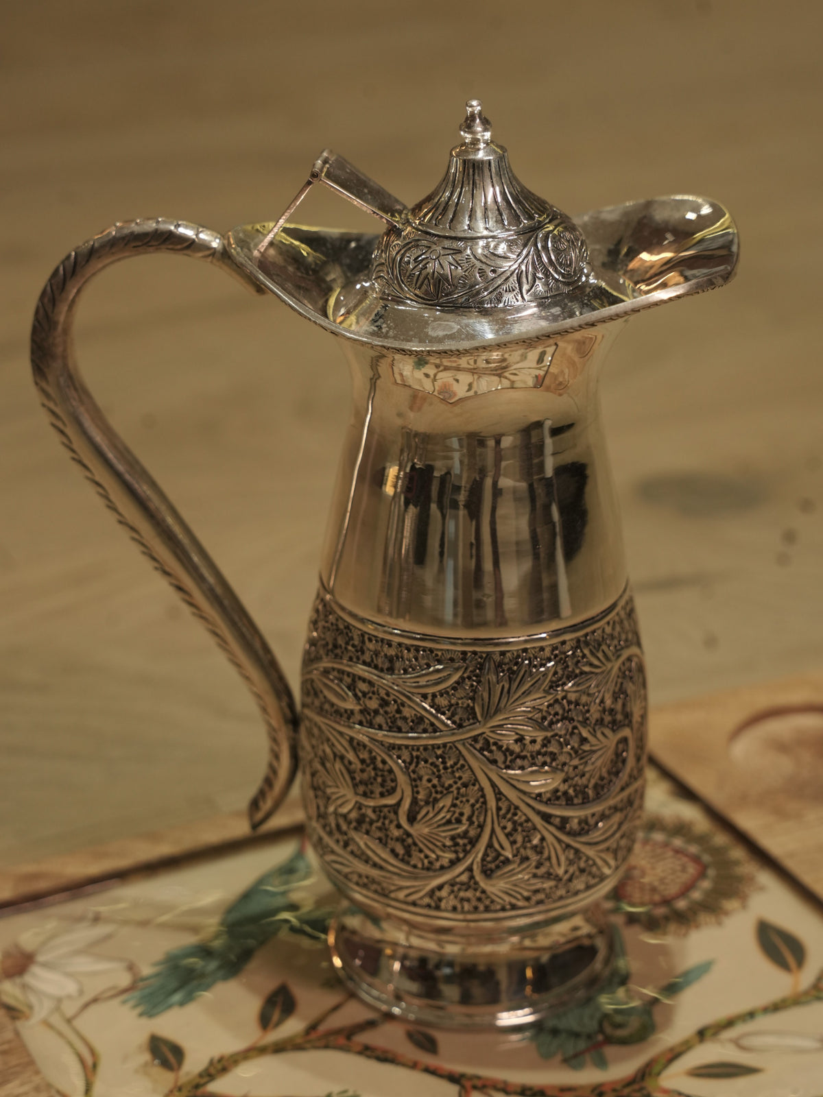 Close view of the chased leaf band around the belly of the silver jug.