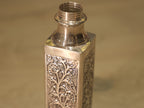 The square silver bottle showing two panelled faces and the round threaded neck.