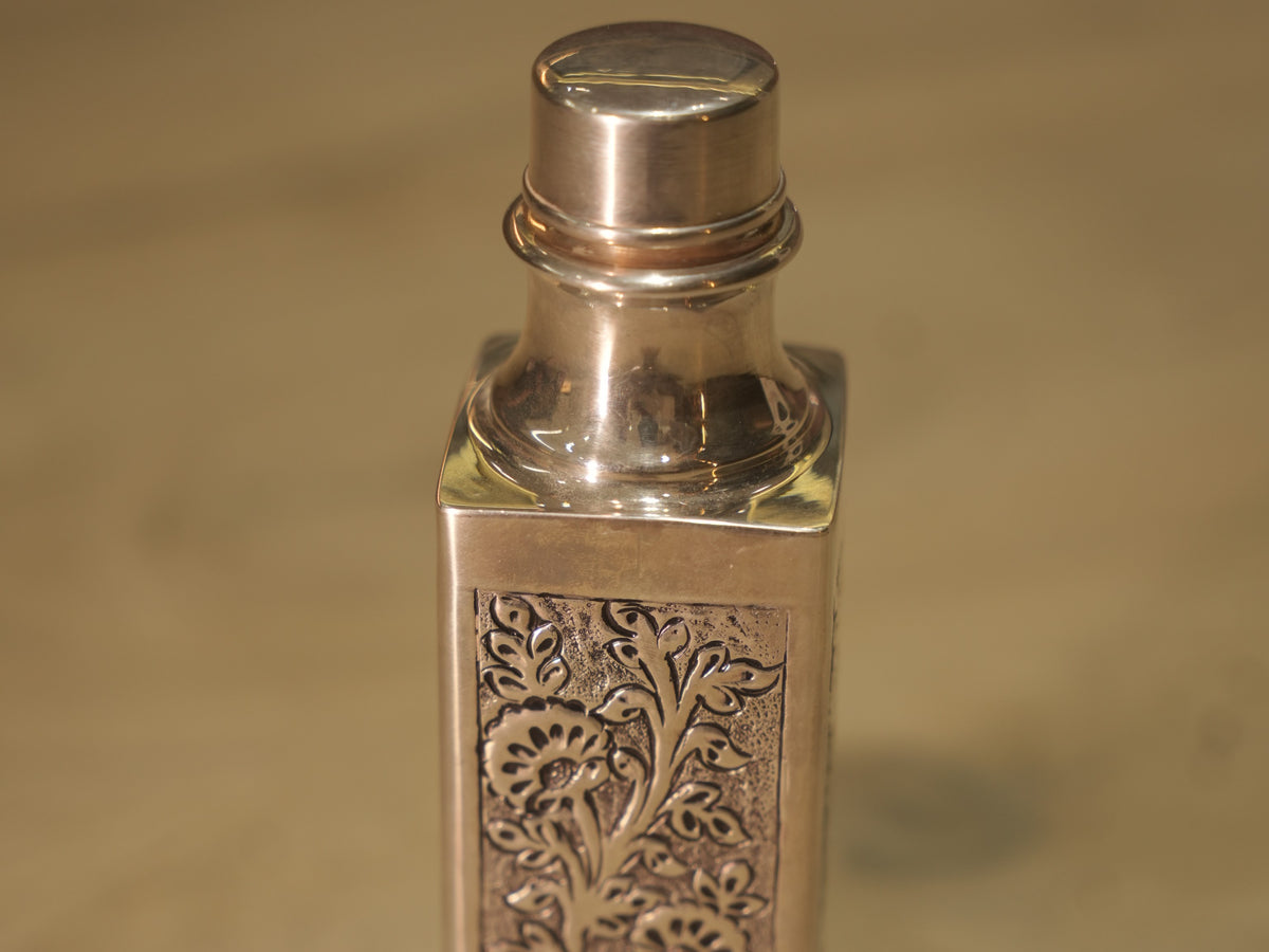 The silver water bottle with its screw cap removed, resting beside it.