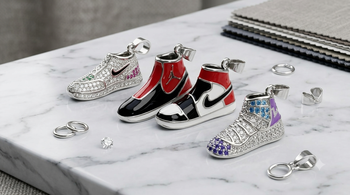 Three silver-tone sneaker-shaped keychains with rhinestone embellishments, displayed on a white marble surface. The keychains are styled like low-top sneakers, featuring silver, red, black, and purple colorways, with silver keyrings and small metal charms scattered around them.